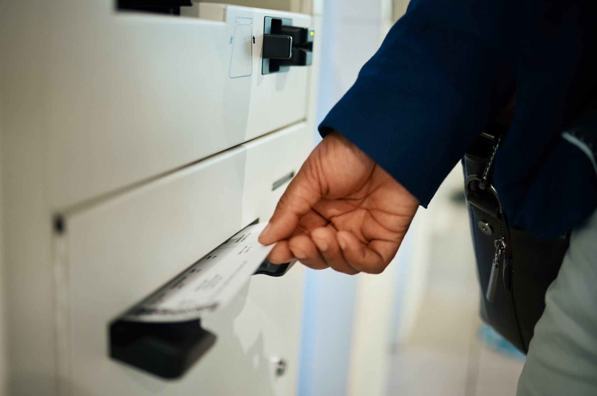 Hands, ticket and airport at self service machine for check in, flight or boarding pass to travel. Hand of traveler taking plane tickets for traveling, trip or journey at airline auto terminal